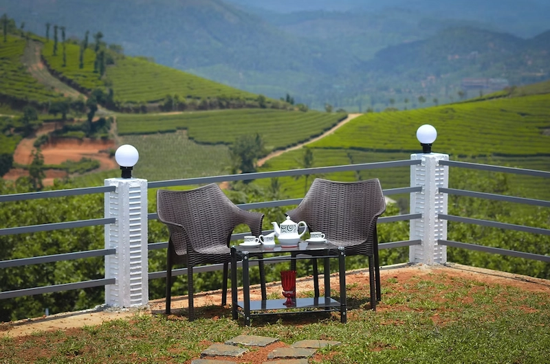 Balcony seating area at The Highlander resort with panoramic tea garden views in Vagamon