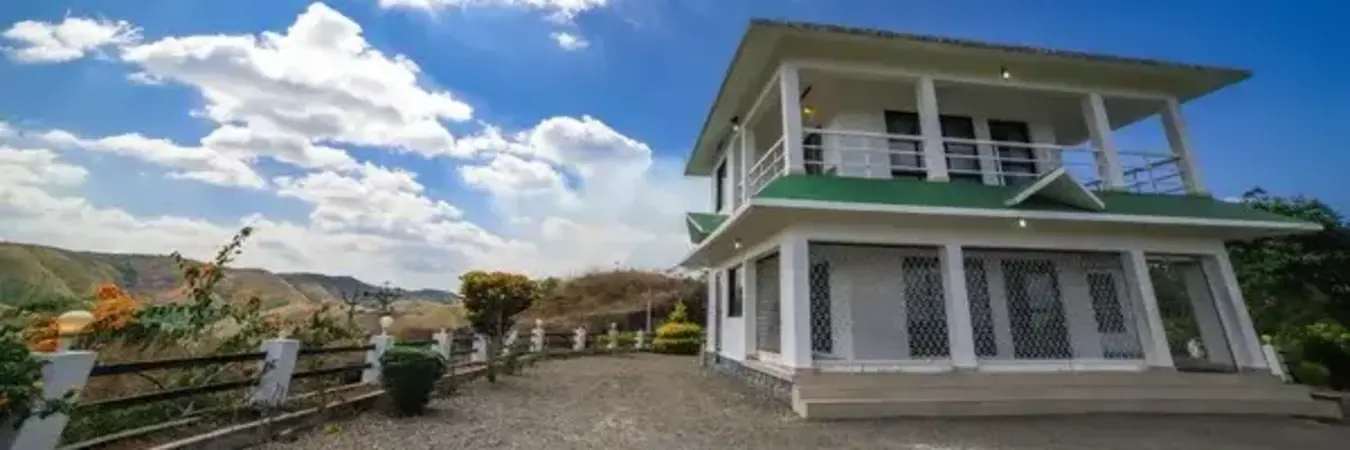 Exterior view of two-story house with green roof and upper deck at The Nest Homestay Vagamon