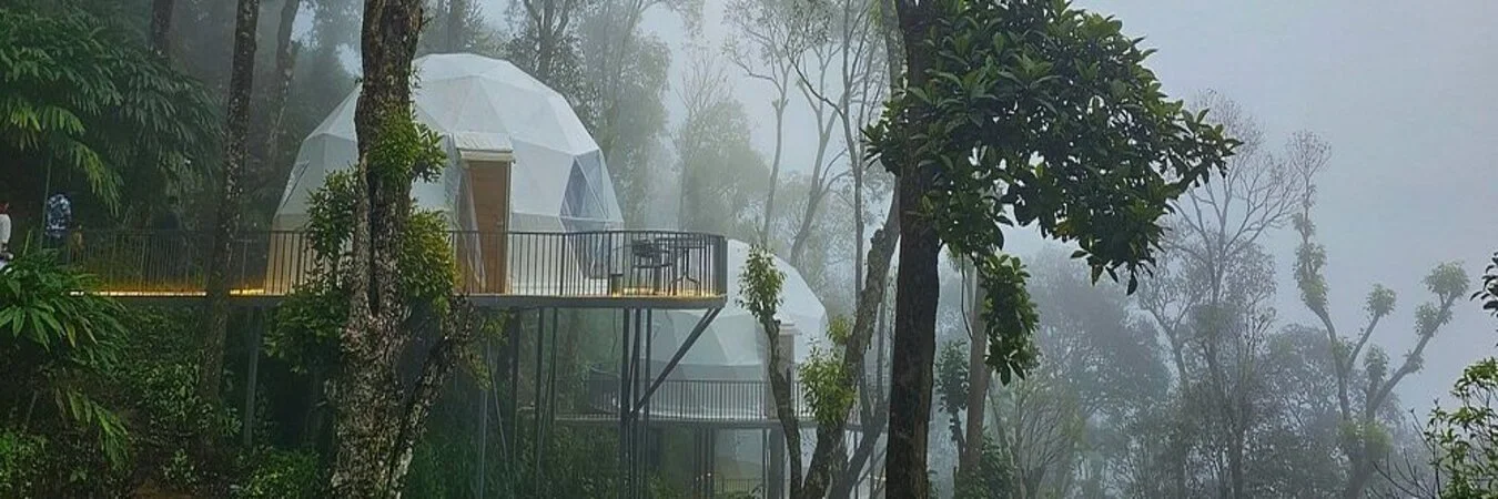 White geodesic dome glamp on elevated deck surrounded by misty forest at Willmount Geodesic Domes Vagamon