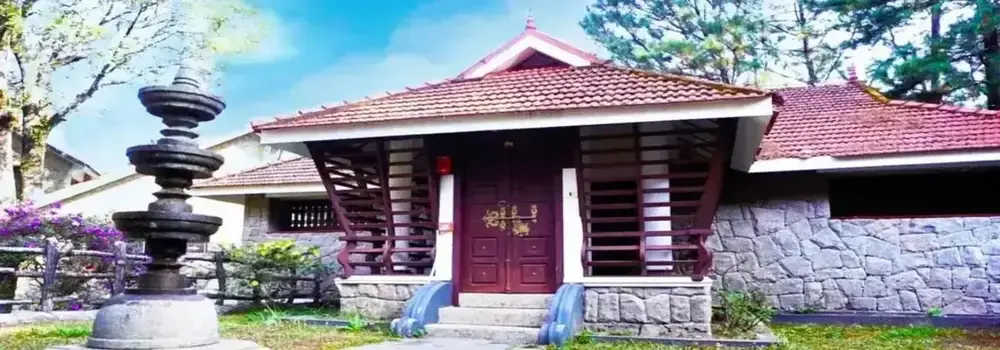 Traditional eco-heritage cottage exterior with stone masonry and red tile roof at Adrak Summer Sand Hill Resort Vagamon