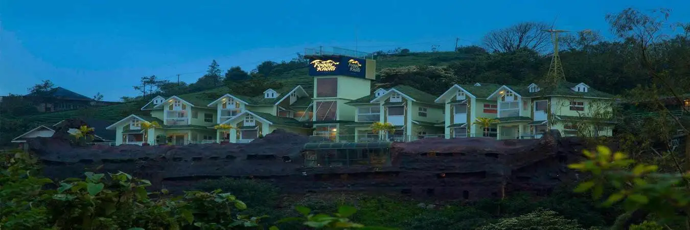 Aerial panoramic view of Foggy Knolls Resort surrounded by lush green mist-covered hills in Vazhikkadavu Vagamon