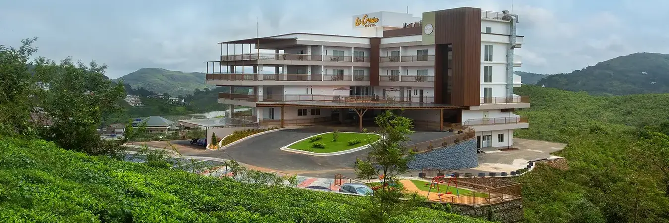 Exterior view of Le Crown Hotel Vagamon surrounded by lush green hills