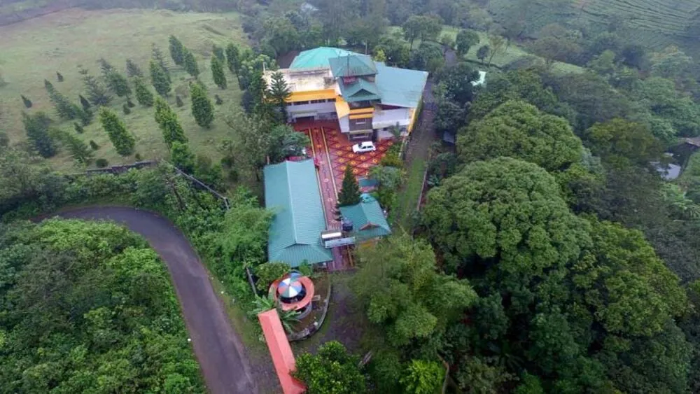 Aerial view of Padmalayam Homestay surrounded by lush green hills and misty valleys in Vagamon