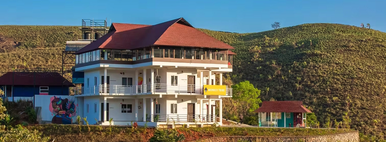 Exterior view of Monkey Tribe Vagamon homestay building on a green hilltop