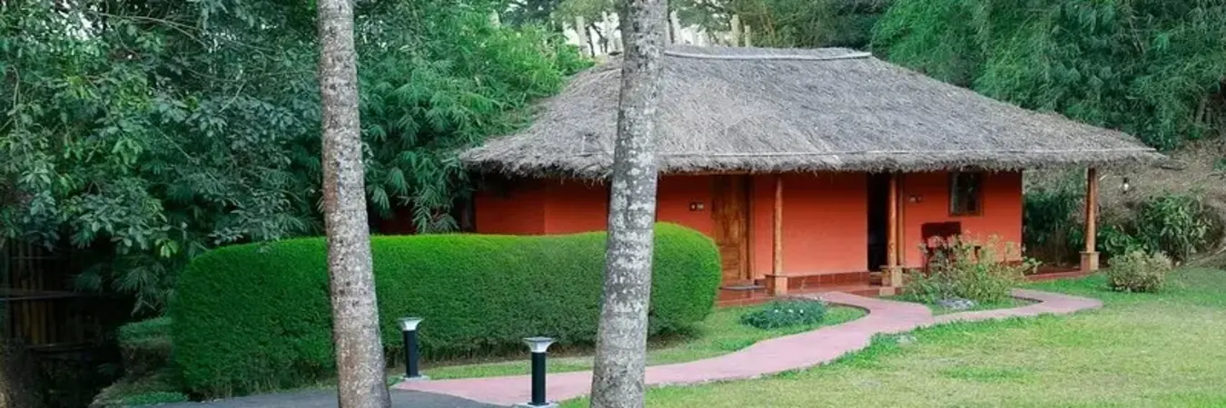 Traditional eco friendly mud cottage surrounded by lush green lawns at SAJ Vagamon Hideout