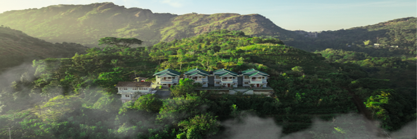 Aerial view of The Autumn by Maat Hotels nestled in misty green hills of Vagamon