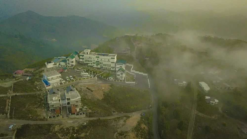 Aerial view of Palette Hill View Resort nestled in misty green Vagamon hills