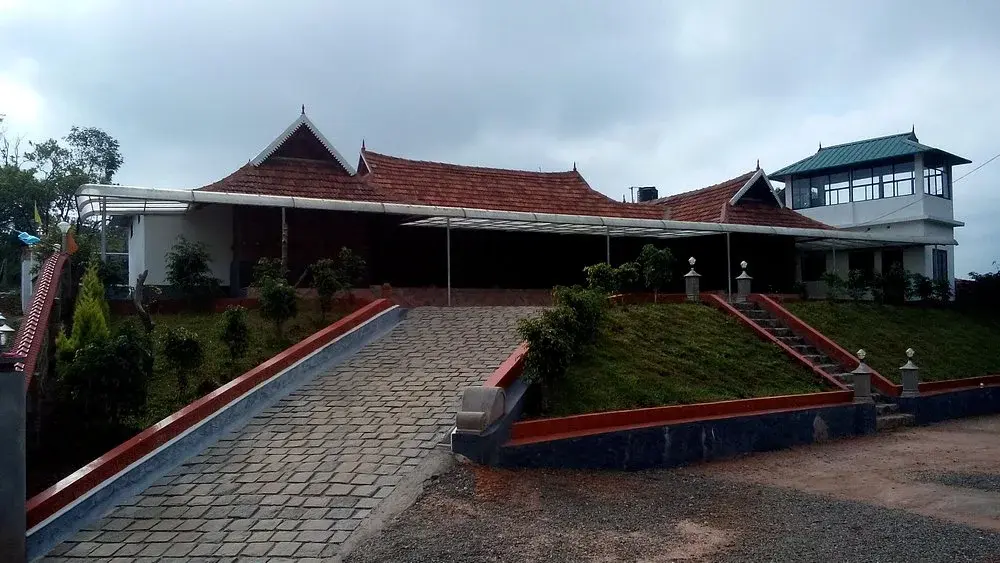 Exterior view of Wood Castle Residency showing traditional Kerala wooden architecture and paved driveway in Vagamon