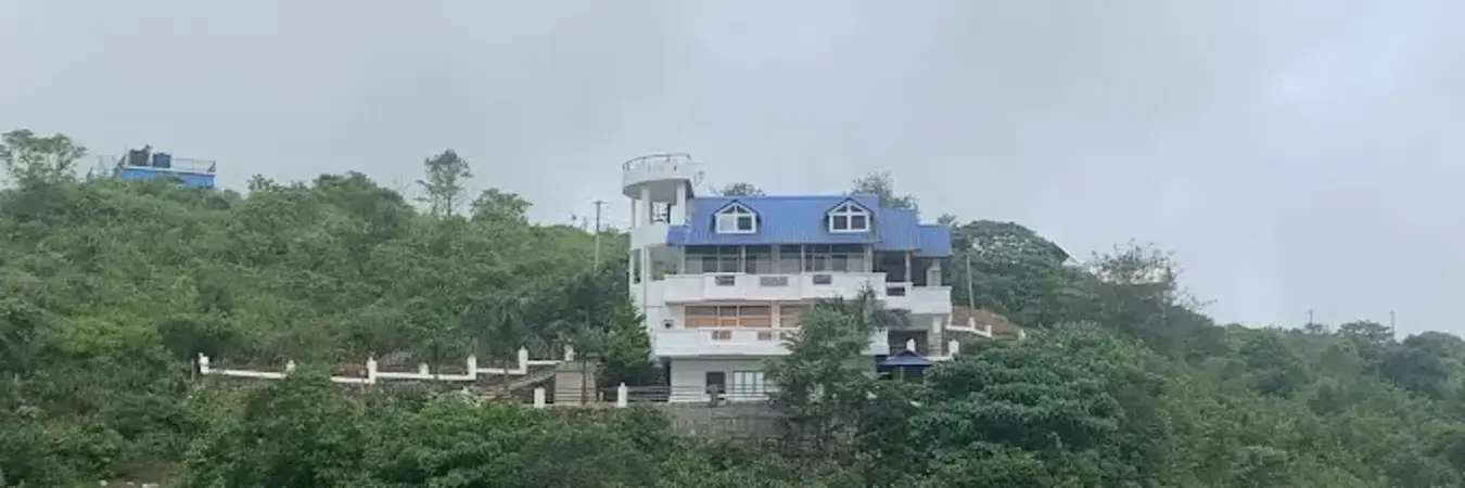 Exterior view of Moon Palace Hillstay building set amidst lush green hills in Vagamon