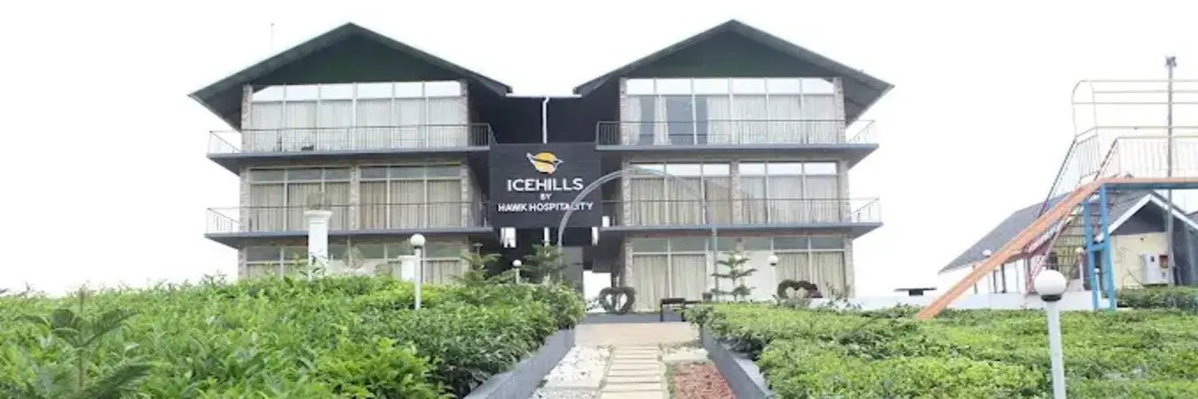Exterior view of modern multi-story building at Ice Hills Resort surrounded by green hills in Vagamon