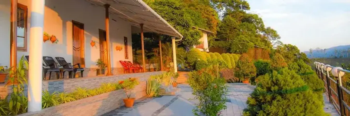 Cottage guest rooms with outdoor porch seating and garden hillside view at Theeram Agro Farm Hill Resort Vagamon