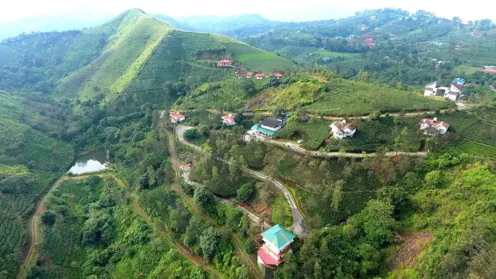 Aerial panoramic view of Falcon Crest Resort nestled among green mountain ridges and tea plantations in Vagamon
