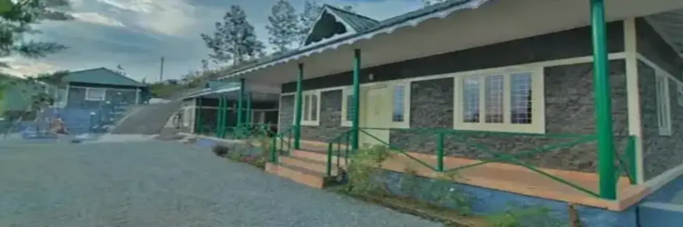 Exterior view of single-story Himaharsham Homestay building with verandah porch and paved yard in Vagamon