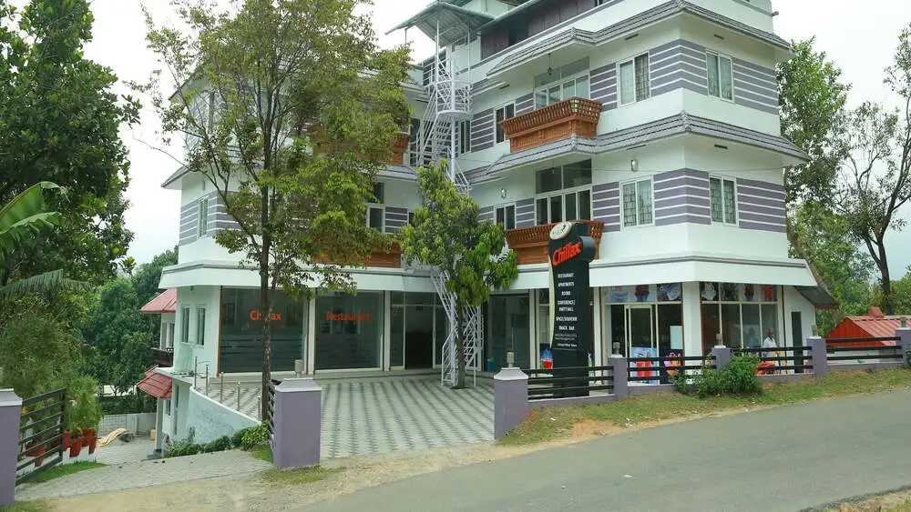 Modern multi-story building exterior of Chillax Vagamon Hotel surrounded by lush greenery in Vagamon