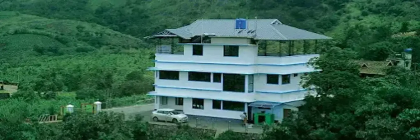 Exterior view of Snow White Residency hotel building surrounded by green mountain hills in Vagamon