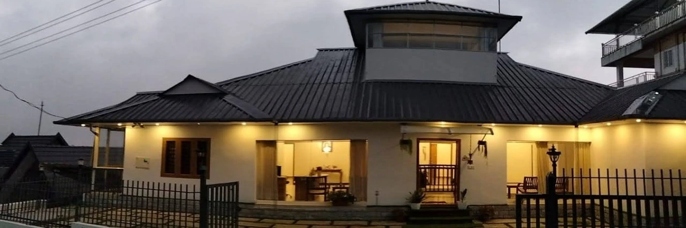 Vagamon Hill Chimes resort building illuminated at dusk surrounded by mist and hills
