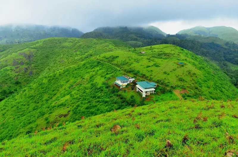 Scenic landscape view of lush green rolling hills and valleys surrounding Dew Drops Holidays in Vagamon