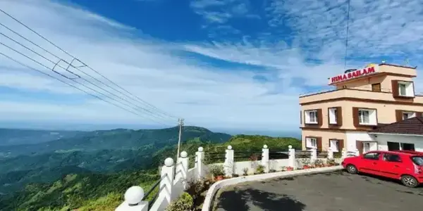 Exterior view of Himasailam Resort building and paved driveway with blue sky in Vagamon