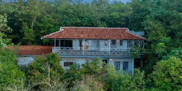 Exterior view of red-tiled roof villa surrounded by dense green forest at Ghats Edge in Vagamon