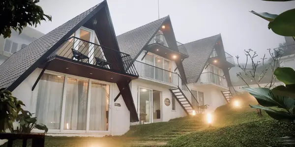 Illuminated luxury A-frame cottages at Trip Mount Vagamon during evening mist