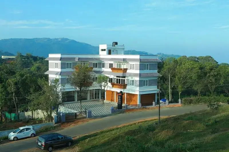 Panoramic daytime view of Chillax Vagamon Hotel set against the rolling hills and green landscape of Vagamon