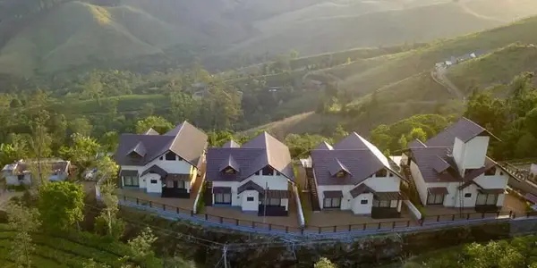 Panoramic hilltop view of villa cottages surrounded by green tea plantations at Beyond Pines Vagamon