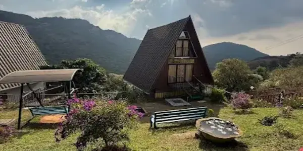 Exterior view of modern dark wooden A-frame cottage surrounded by green hills at JMount Vagamon Resort