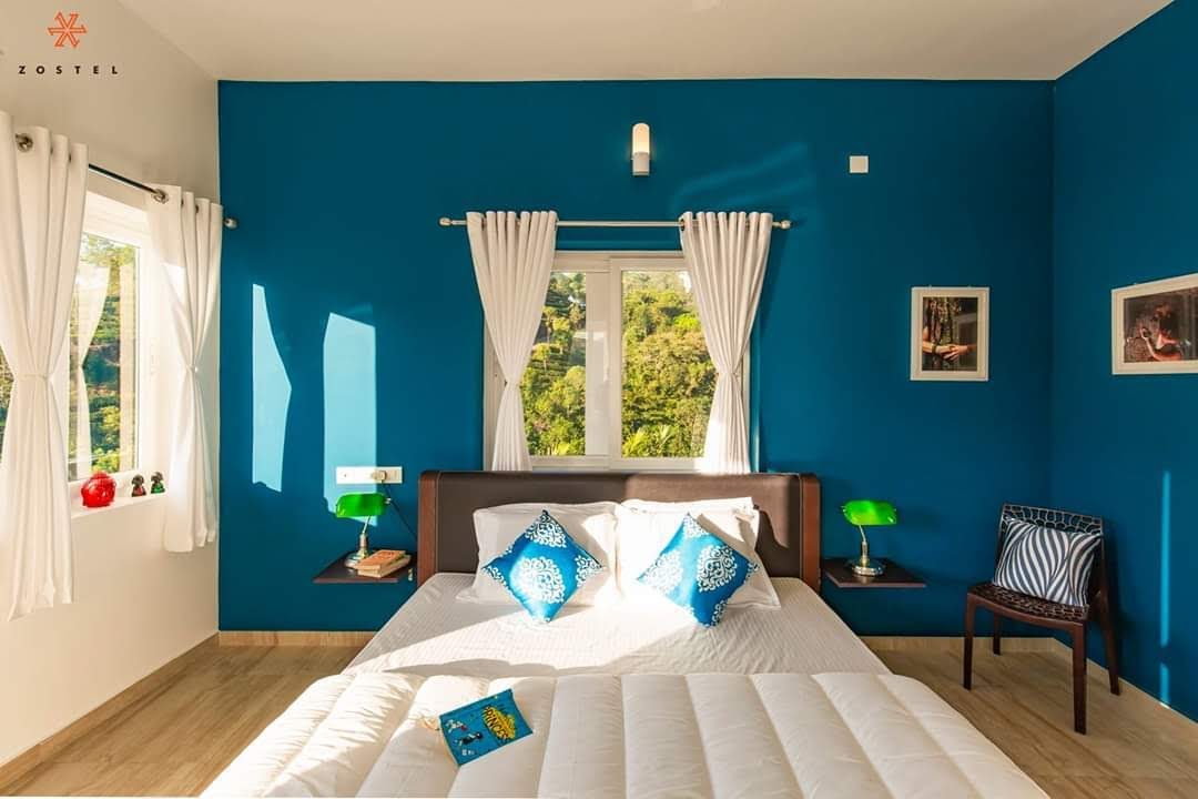 Cozy bedroom interior with blue accent wall and window view at Monkey Tribe Vagamon