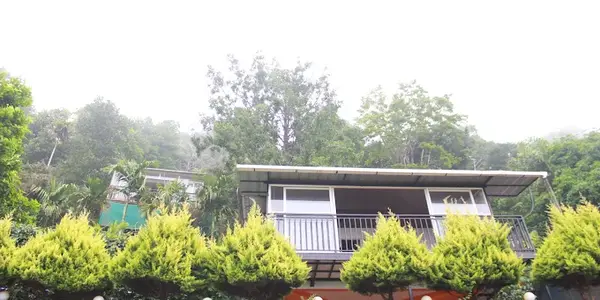 Exterior view of modern hill cottage with sloped roof and potted garden plants at Theeram Agro Farm Hill Resort