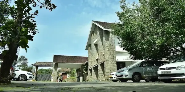 Exterior view of resort building with stone wall architecture and guest parking at Adrak Summer Sand Hill Resort Vagamon