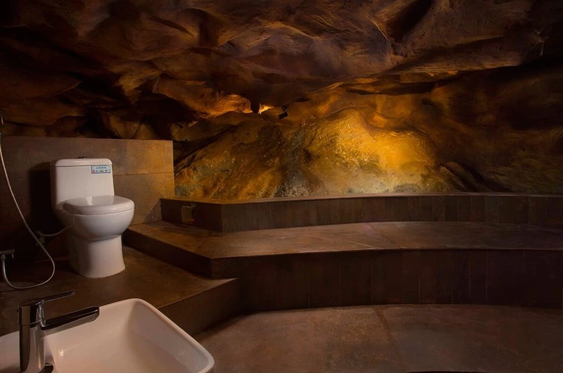 Unique cave-themed en-suite bathroom featuring natural stone textured walls and modern amenities at Foggy Knolls Resort