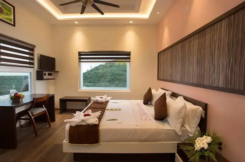 Spacious luxury suite bedroom featuring a plush double bed, wooden wall panels, and ambient ceiling lighting