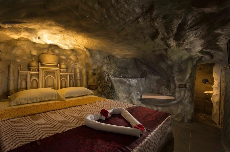 Cozy honeymoon suite bedroom featuring a plush double bed, warm ambient lighting, and unique cave-inspired wall decor at Foggy Knolls Resort