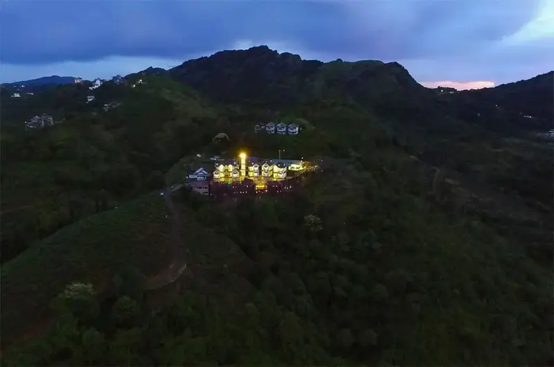 Scenic hilltop dusk view of Foggy Knolls Resort with glowing property signboard against the twilight sky