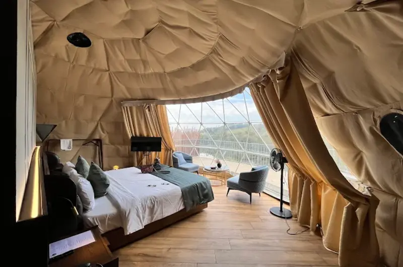 Cozy glamping dome bedroom with modern interior design, plush bedding, and natural hillside light