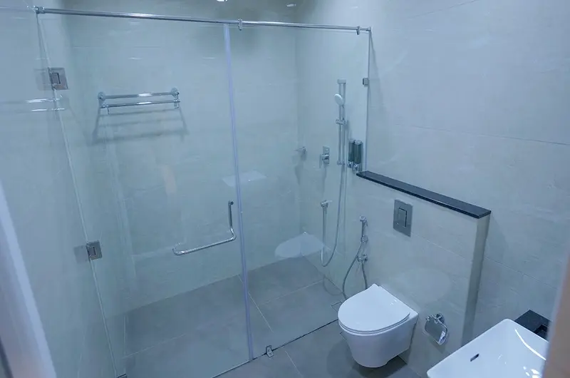 Clean modern bathroom with glass shower enclosure, tiled walls, and modern sanitary fittings at Palette Hill View Resort Vagamon