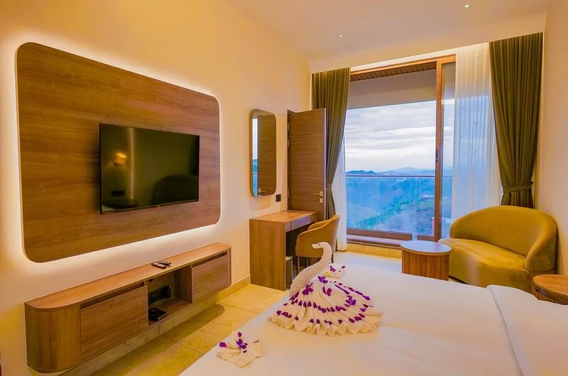 Decorated honeymoon suite bedroom with swan towel art, plush double bed, and private balcony view at Palette Hill View Resort
