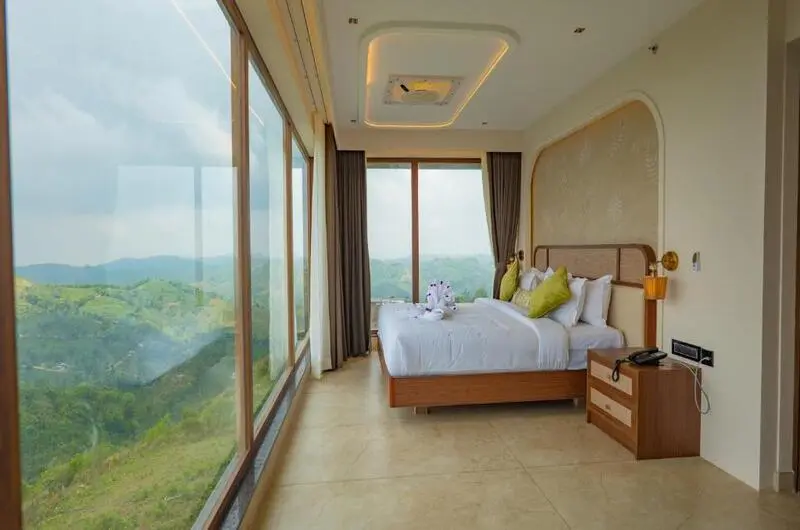 Deluxe bedroom suite featuring a king-size bed and private balcony overlooking Vagamon green hills