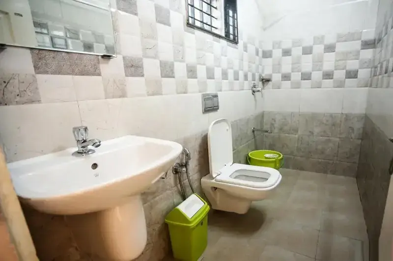 Clean attached modern bathroom with wall tiles, pedestal sink, and modern sanitary fittings at Lavender Plantation Stay