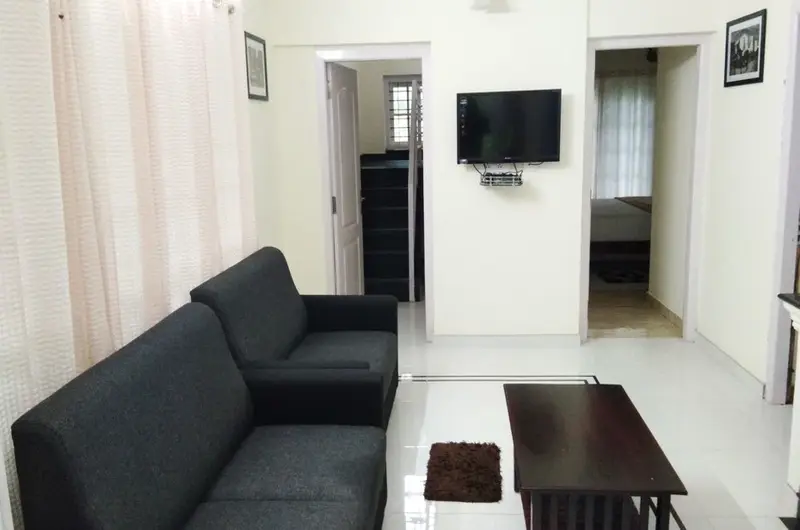 Spacious indoor living area featuring comfortable dark sofas and television unit at Lavender Plantation Stay