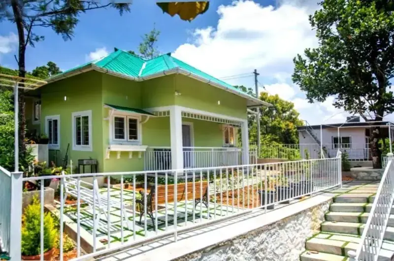 Exterior front view of green cottage building with paved steps at Lavender Plantation Stay Vagamon