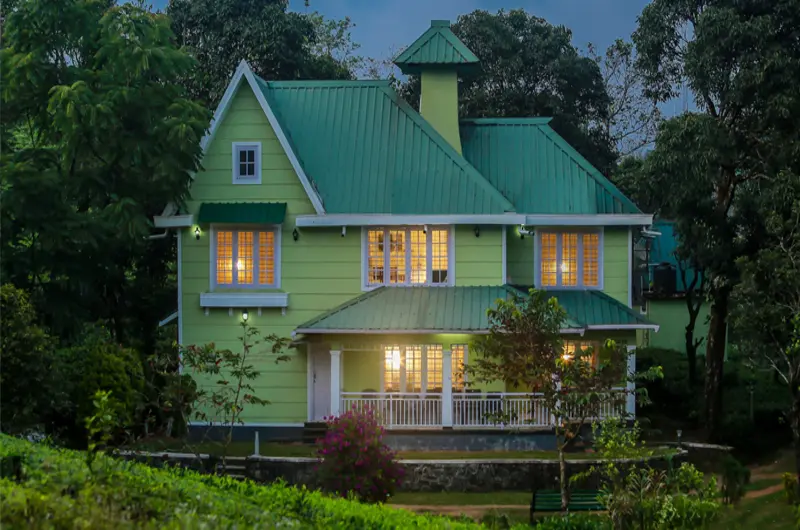 Evening dusk view of green cottage building illuminated by warm lights at Lavender Plantation Stay