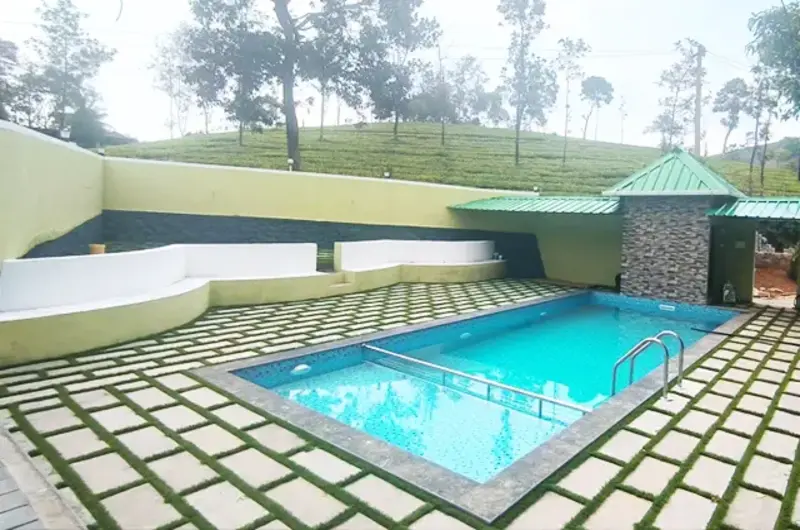 Outdoor swimming pool with sun loungers overlooking lush green trees at Lavender Plantation Stay