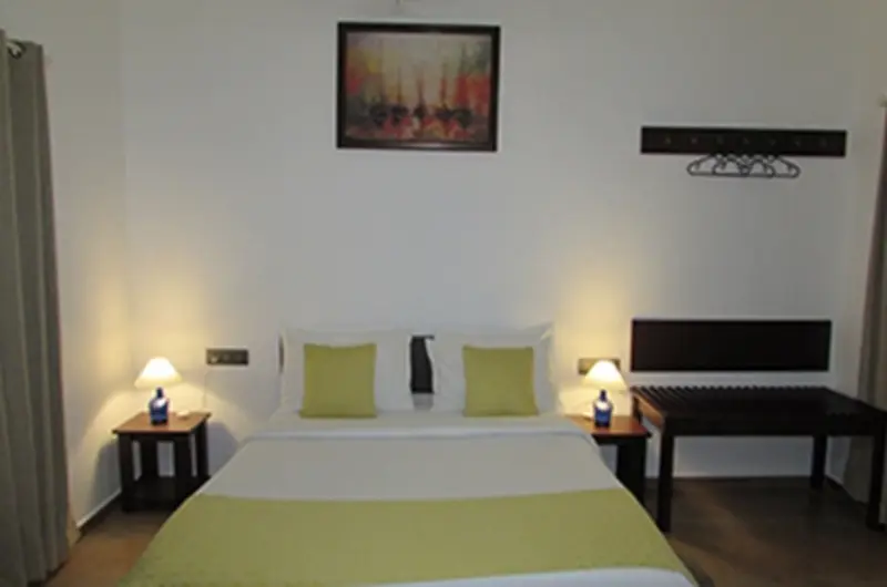 Deluxe resort bedroom featuring twin double beds with green accents and warm ambient wall lights