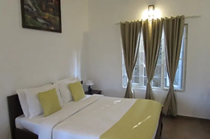 Cozy guest room with plush bed, lime yellow runner, wall sconce lighting, and curtains at Falcon Crest Resort