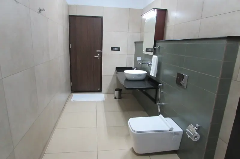 Clean guest bathroom featuring modern wall tiles, glass counter sink, and modern sanitary fittings at Falcon Crest Resort Vagamon