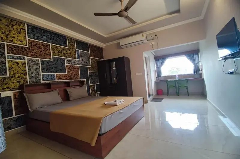 Spacious resort guest bedroom with plush bedding, patterned wallpaper, and warm ceiling lighting at Green Palace Residency