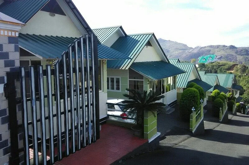 Exterior view of multi-story cottage architecture at Green Palace Residency set against blue skies