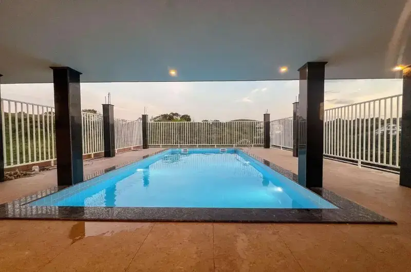 Outdoor swimming pool with tiled deck area surrounded by glass railings at Green Palace Residency