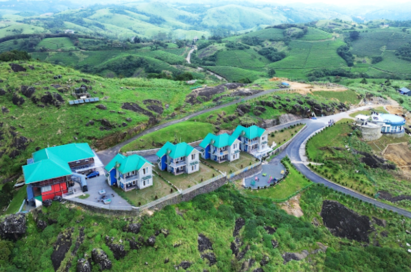 Aerial view of Orange Valley Hills Resort nestled among green mountain slopes and tea plantations in Vagamon
